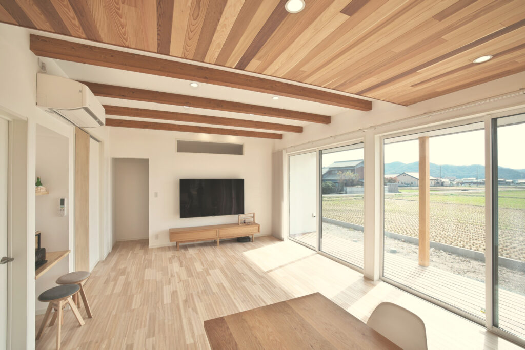 大きな窓から田園風景が見える、明るい木の天井のLDK（丸尾建築の施工事例