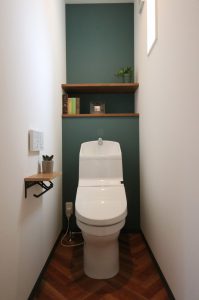 クラシカルな“ヘリンボーン”床と渋めのグリーンのアクセントクロスがかっこいいトイレ