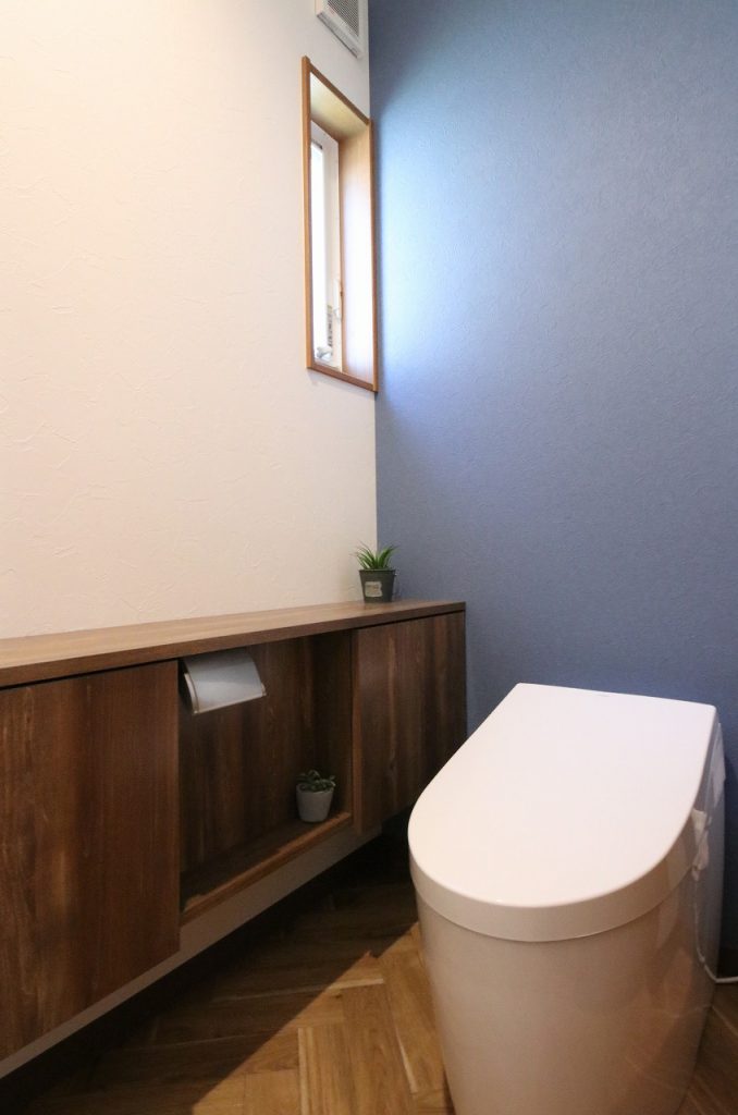 トイレにもヘリンボーンの床を採用。 深い藍色のアクセントクロスでクラシカルで上品な雰囲気に。