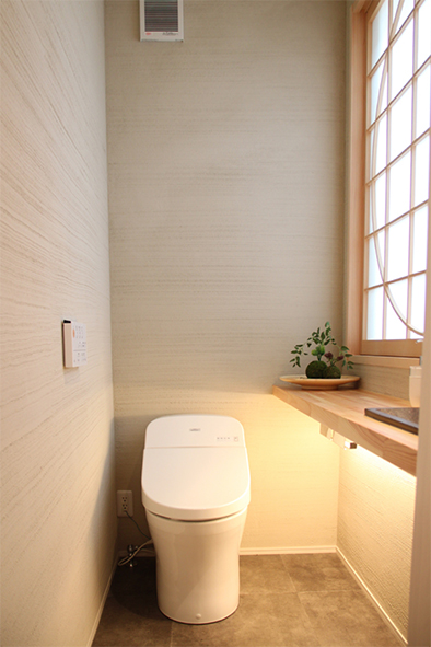 壁は薩摩中霧島を使用した和テイストのトイレ。坪庭に面した窓から木陰が映る