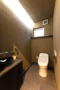 間接照明のほんのりした光のグラデーションが楽しめるトイレ。室内は、デザイン性だけでなく、調湿・消臭効果もある薩摩中霧島で仕上げています。