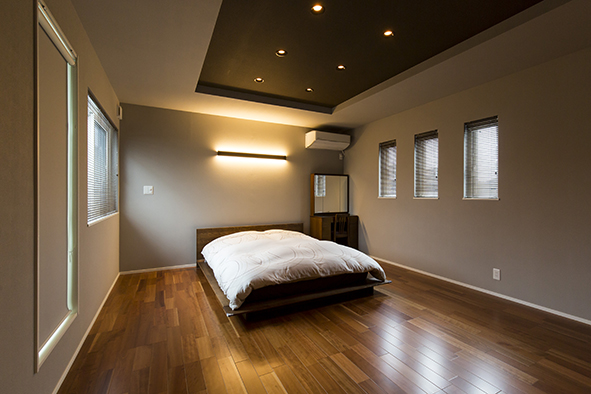 ブランベースのシックな落ち着いた寝室。折り上げ天井と間接照明も設けゆったりくつろげる空間に。