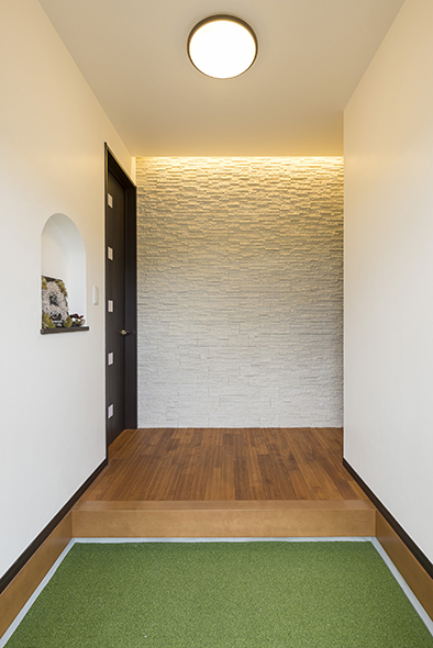 正面の石張り壁に間接照明を入れた玄関ホール。凹凸に光が当たり幻想的に。