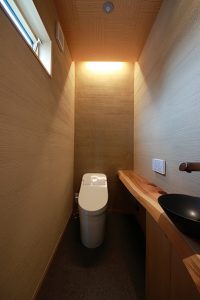 壁は薩摩中霧島を使用した「和モダン」のトイレ。間接照明とピンスポットダウンライトで落ち着いた空間に。
