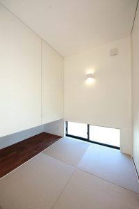 淡いグレーの畳で仕上げた和室。吊り収納の下とリビングの床と同じものを使用し、リビングとの一体感がでるようにコーディネート。